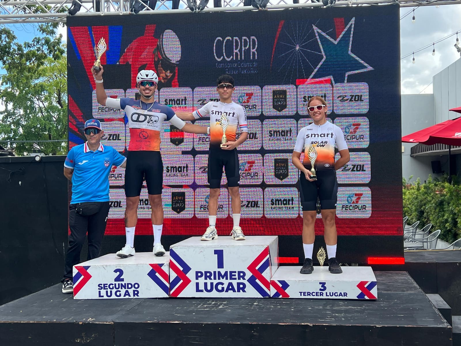 Dos atletas de Smart Racing Team suben al podio junto a un competidor de otro equipo en la Copa Olímpica