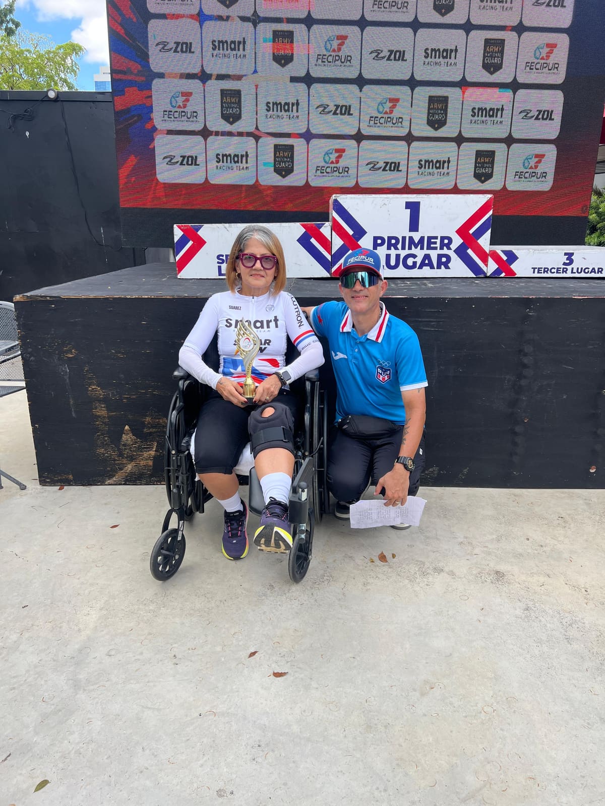 Atleta de Smart Racing Team posa con su trofeo junto a un oficial de la FECIPUR